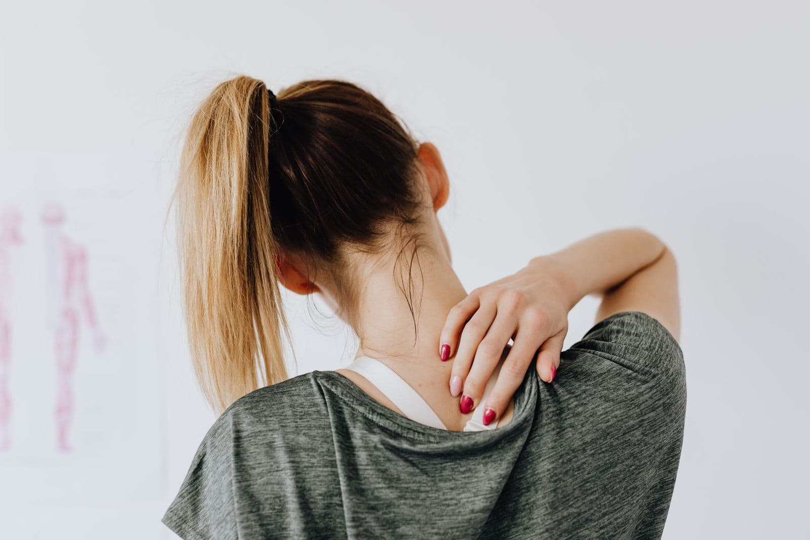 Woman holding her neck in pain — upper crossed syndrome, tech neck, and forward head posture, Forest Hills Queens NY