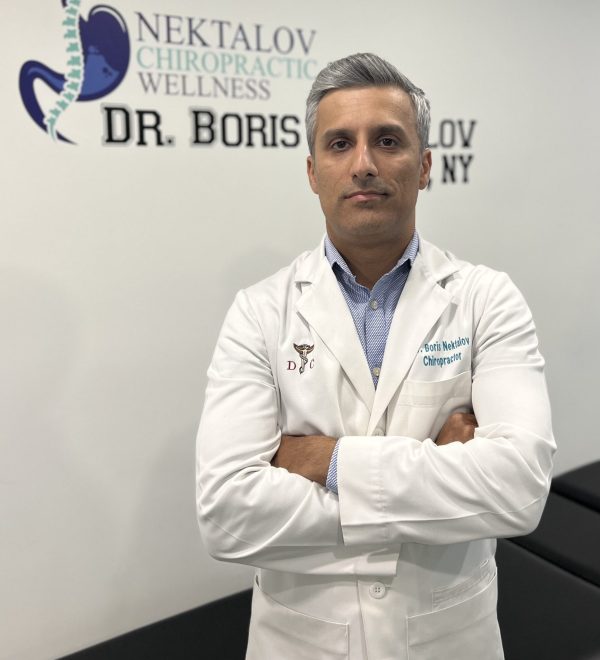 A man in white lab coat standing next to a wall.